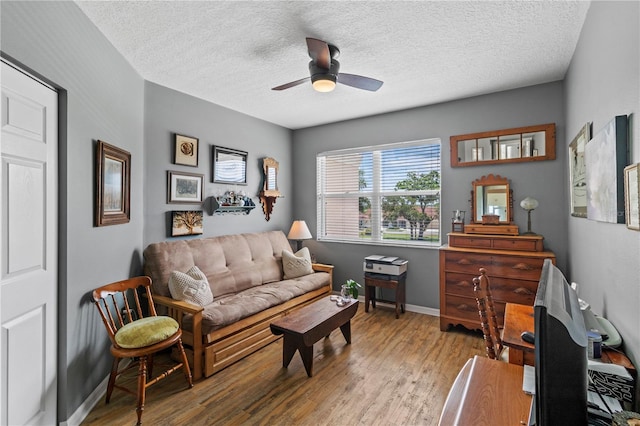 living area featuring light hardwood / wood-style flooring, ceiling fan, and a textured ceiling