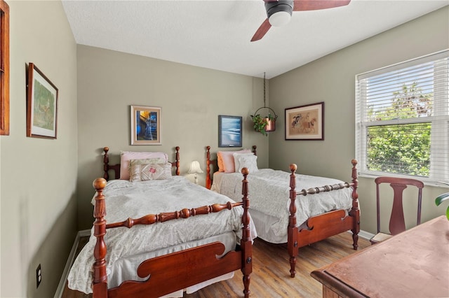 bedroom with light wood-type flooring, ceiling fan, and a textured ceiling