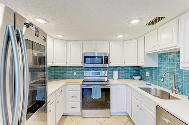 kitchen with stainless steel appliances, white cabinets, a textured ceiling, and sink