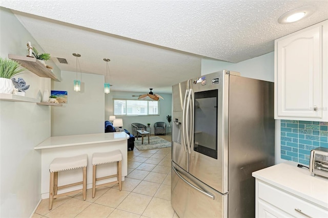 kitchen with pendant lighting, light tile patterned flooring, a textured ceiling, white cabinetry, and stainless steel refrigerator with ice dispenser