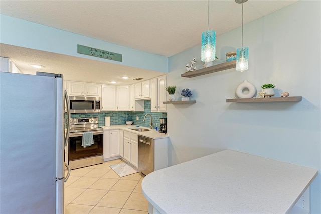 kitchen with sink, white cabinetry, hanging light fixtures, stainless steel appliances, and light tile patterned floors