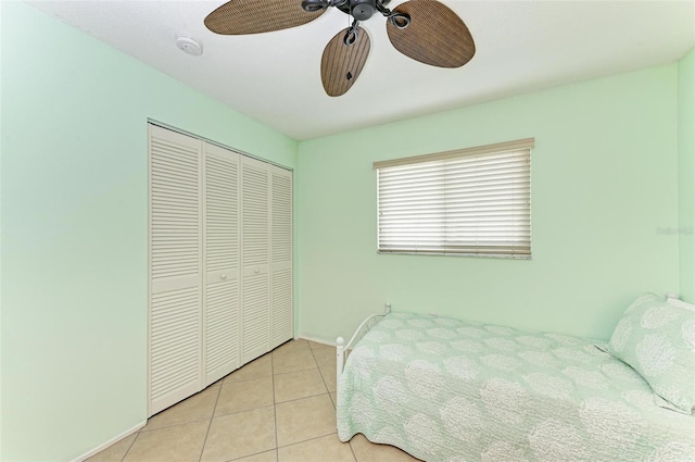 bedroom featuring a closet, a ceiling fan, baseboards, and light tile patterned floors