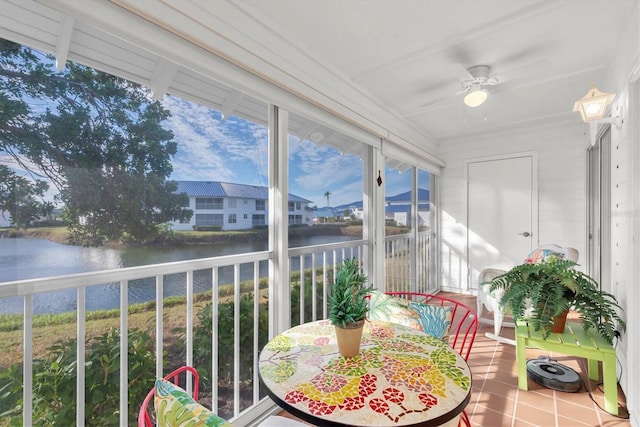 sunroom with ceiling fan and a water view