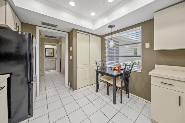 kitchen with black fridge, a raised ceiling, light tile patterned floors, decorative light fixtures, and crown molding