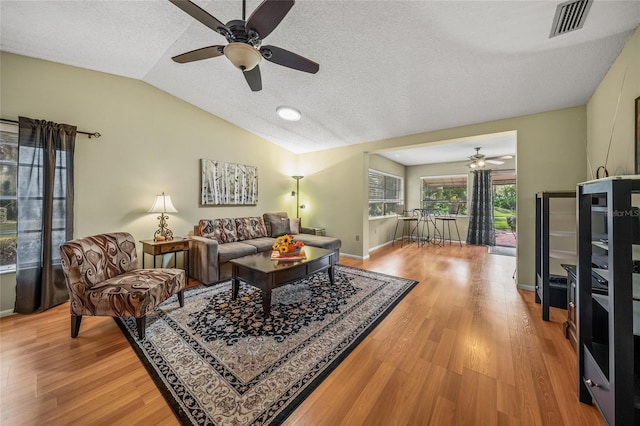 living room featuring lofted ceiling, hardwood / wood-style flooring, a textured ceiling, and ceiling fan