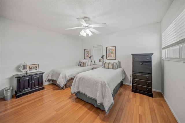 bedroom with hardwood / wood-style flooring, ceiling fan, and a textured ceiling