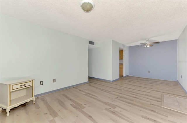 spare room with a textured ceiling, light hardwood / wood-style floors, and ceiling fan