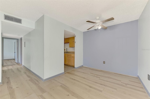 empty room featuring light hardwood / wood-style flooring, a textured ceiling, and ceiling fan