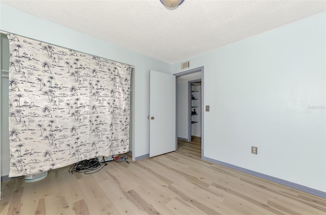 spare room featuring a textured ceiling and light hardwood / wood-style flooring