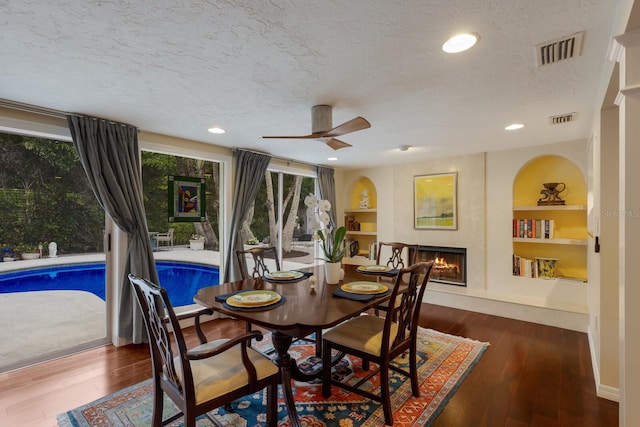 dining space featuring ceiling fan, hardwood / wood-style flooring, built in features, and a textured ceiling