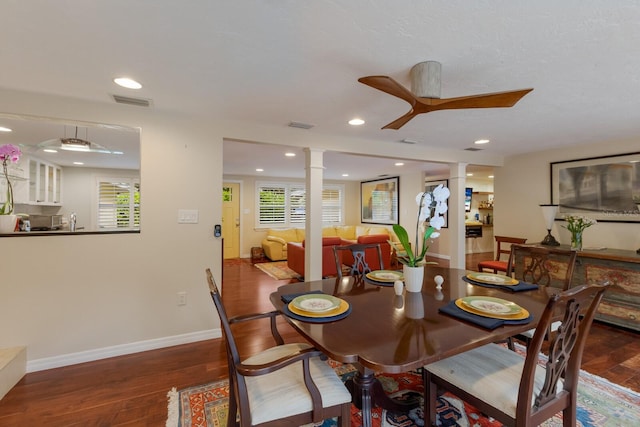 dining space featuring a healthy amount of sunlight, ceiling fan, dark wood-type flooring, and ornate columns