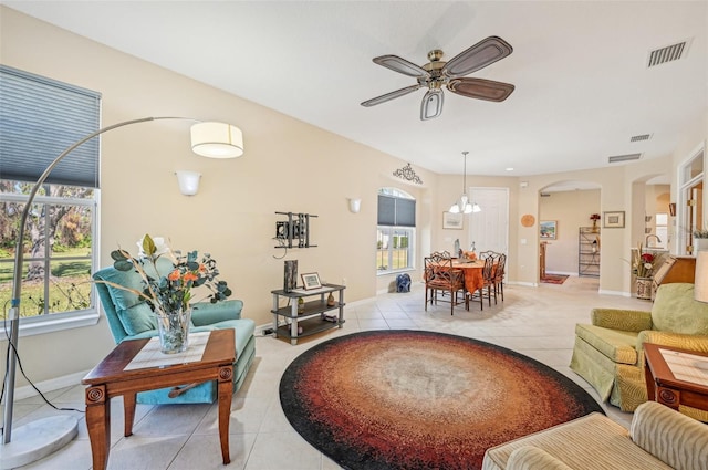 living room with ceiling fan with notable chandelier and light tile patterned floors