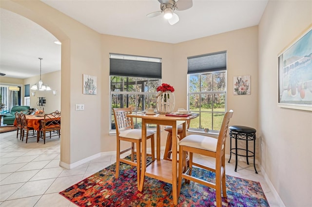 tiled dining space featuring a healthy amount of sunlight and ceiling fan with notable chandelier