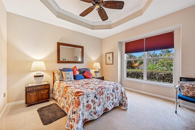 carpeted bedroom featuring ornamental molding, ceiling fan, and a raised ceiling