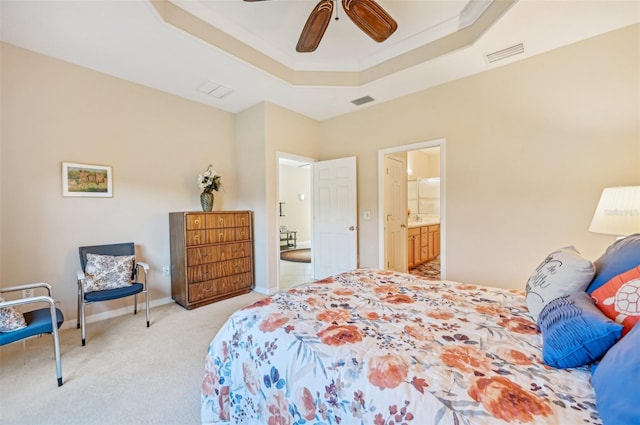 carpeted bedroom with ornamental molding, ensuite bath, ceiling fan, and a raised ceiling