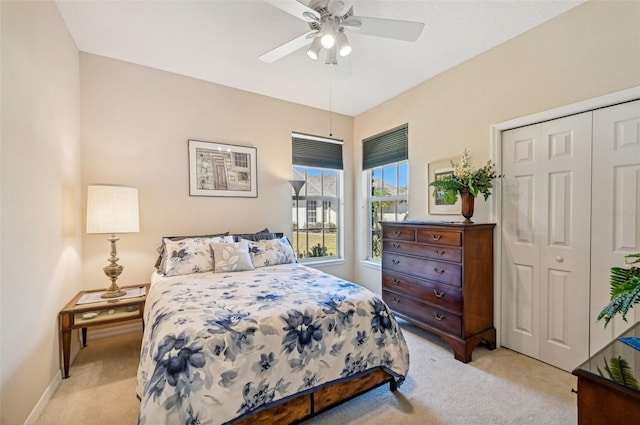 bedroom with ceiling fan, light carpet, and a closet