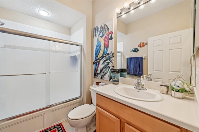 full bathroom with vanity, bath / shower combo with glass door, a textured ceiling, and toilet