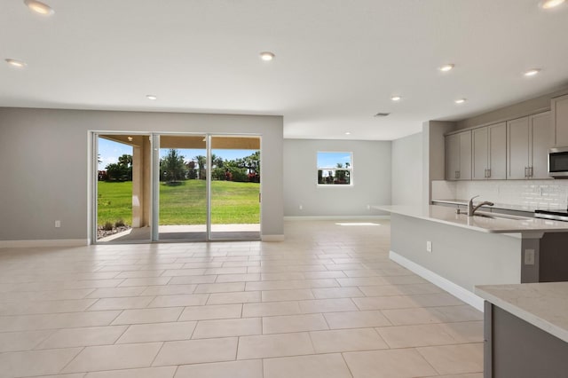 kitchen featuring gray cabinetry, light tile patterned flooring, decorative backsplash, and stainless steel appliances