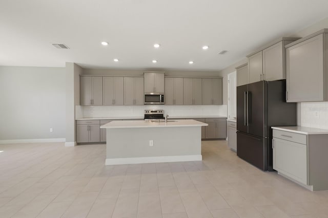 kitchen with gray cabinetry, an island with sink, appliances with stainless steel finishes, and sink