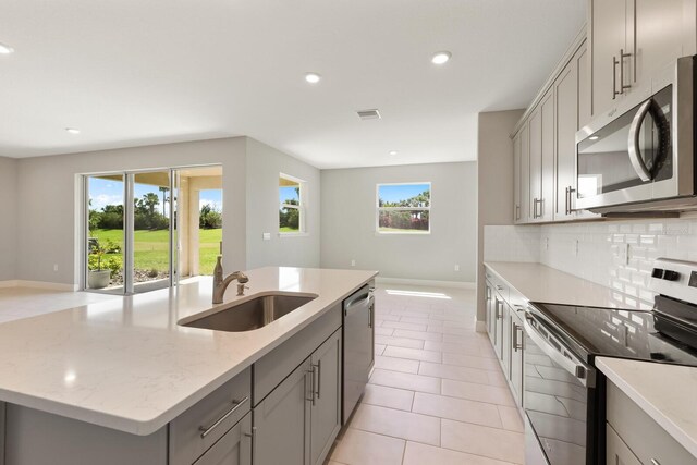 kitchen featuring a center island with sink, appliances with stainless steel finishes, sink, and a healthy amount of sunlight