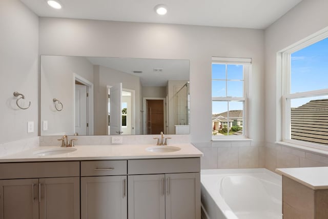 bathroom with a wealth of natural light, independent shower and bath, and vanity