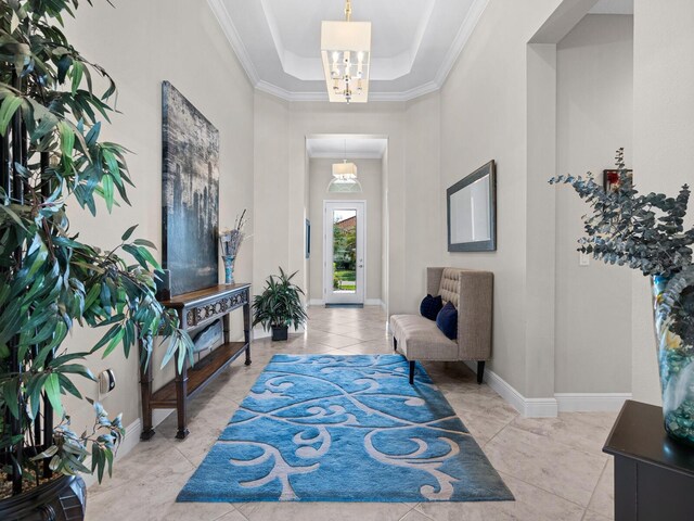 tiled foyer entrance featuring a tray ceiling and ornamental molding