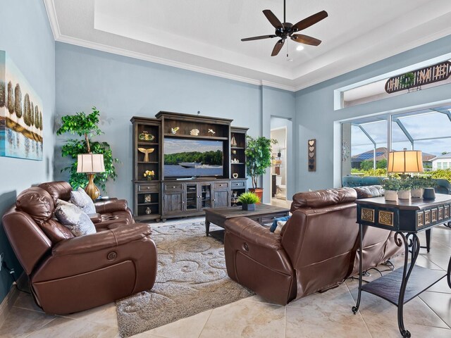 tiled living room with a towering ceiling, ceiling fan, crown molding, and a tray ceiling