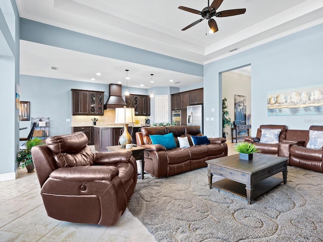 living room with light tile patterned floors, ceiling fan, a tray ceiling, and ornamental molding