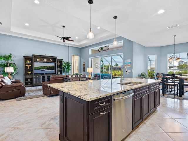 kitchen with sink, decorative light fixtures, an island with sink, a raised ceiling, and dishwasher