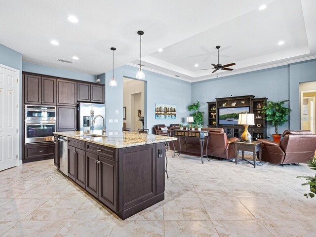 kitchen with pendant lighting, appliances with stainless steel finishes, sink, and a tray ceiling