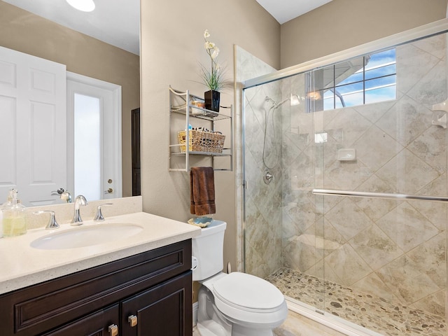 bathroom with walk in shower, vanity, and toilet