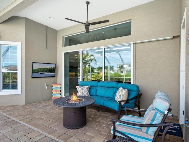 view of patio / terrace featuring ceiling fan and an outdoor living space with a fire pit