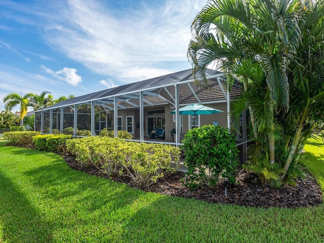 back of property with a patio, a yard, and a lanai