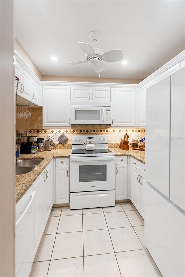 kitchen with white cabinets, decorative backsplash, and white appliances