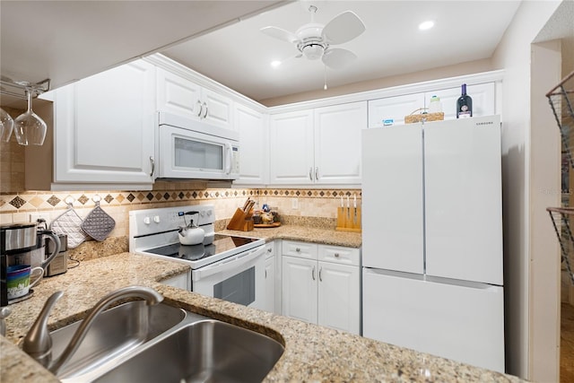 kitchen with tasteful backsplash, light stone counters, white appliances, sink, and white cabinets