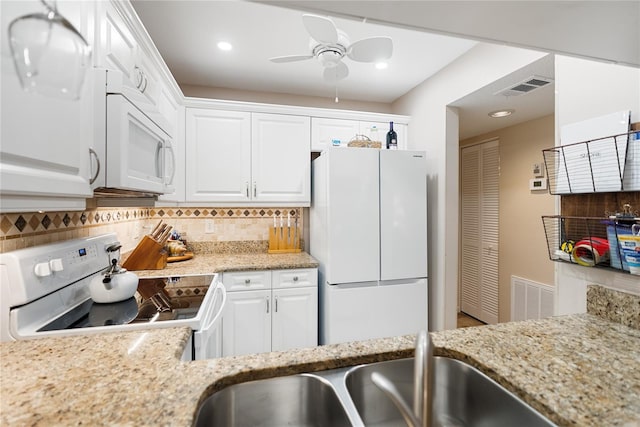 kitchen featuring tasteful backsplash, white cabinets, and white appliances