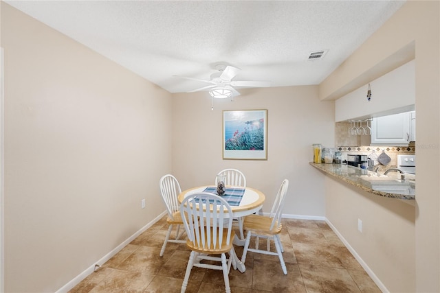 dining area featuring ceiling fan, light tile patterned flooring, and a textured ceiling