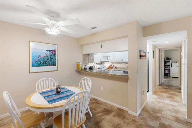 tiled dining area with a textured ceiling and ceiling fan