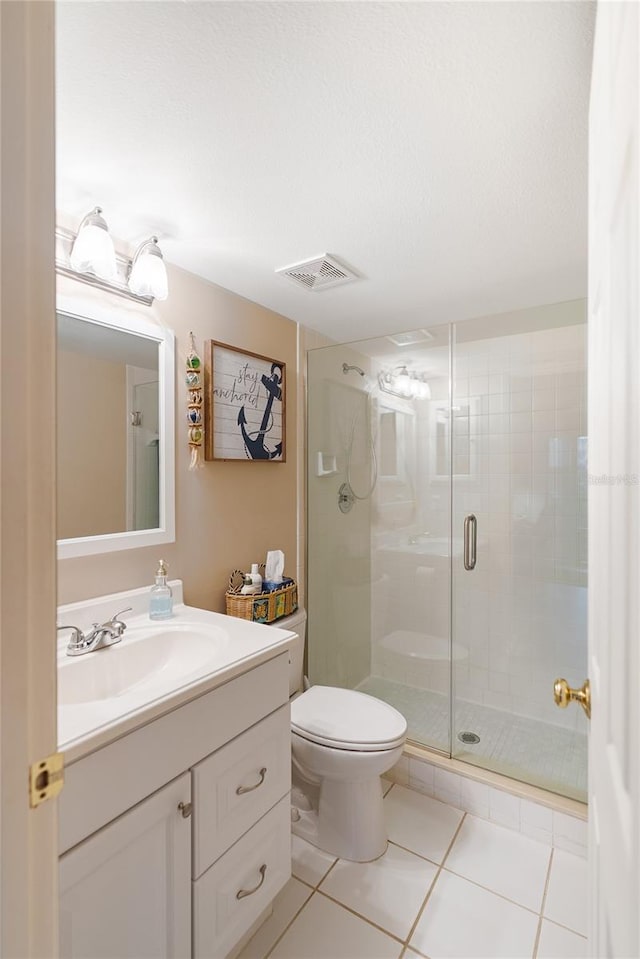 bathroom featuring toilet, vanity, tile patterned floors, and a shower with door