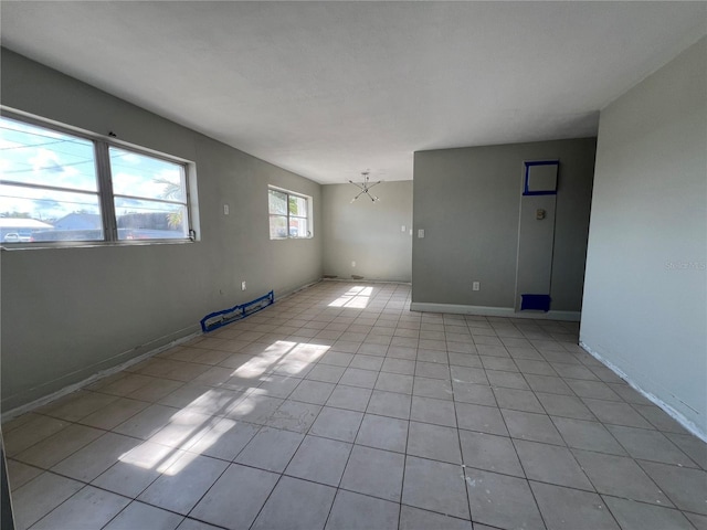 unfurnished room featuring a chandelier, baseboards, and light tile patterned floors