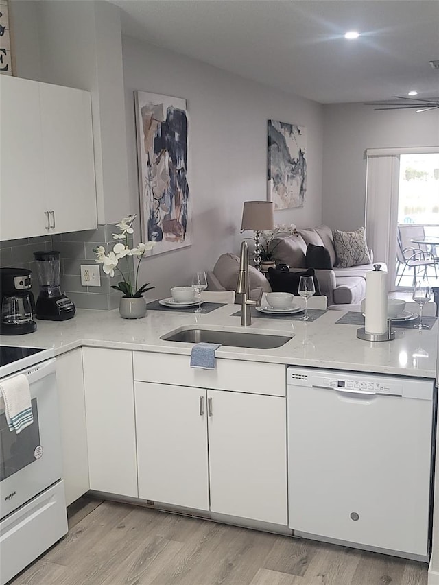 kitchen featuring decorative backsplash, white cabinets, white appliances, light wood-type flooring, and sink