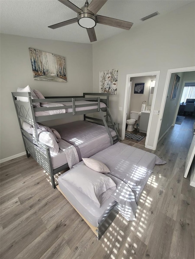 bedroom featuring connected bathroom, lofted ceiling, ceiling fan, and hardwood / wood-style floors