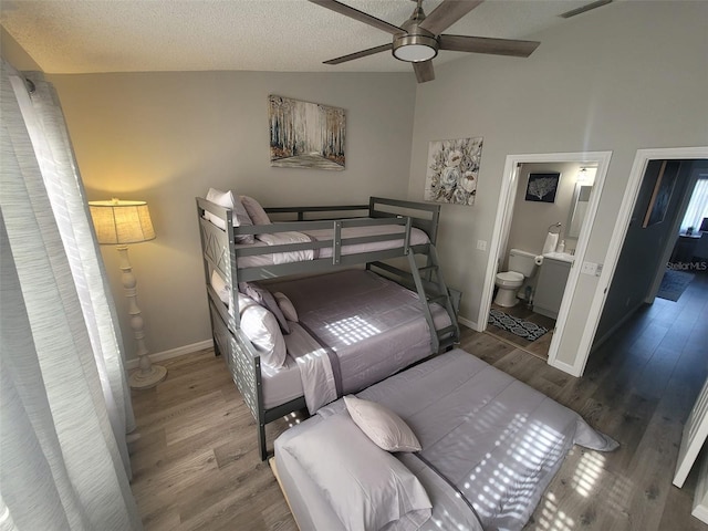 bedroom with vaulted ceiling, connected bathroom, a textured ceiling, ceiling fan, and hardwood / wood-style flooring