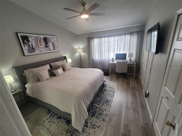 bedroom featuring ceiling fan, a textured ceiling, hardwood / wood-style floors, and vaulted ceiling