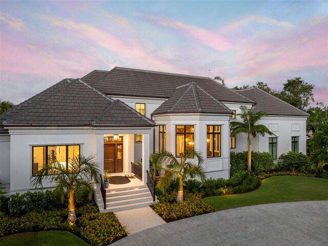 501 Harbor Point Rd, Longboat Key, FL 34228 - view of front facade with a tiled roof, stucco siding, and a lawn