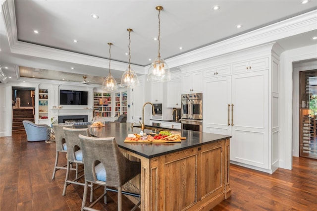 kitchen with hanging light fixtures, dark wood-type flooring, white cabinetry, a spacious island, and stainless steel double oven