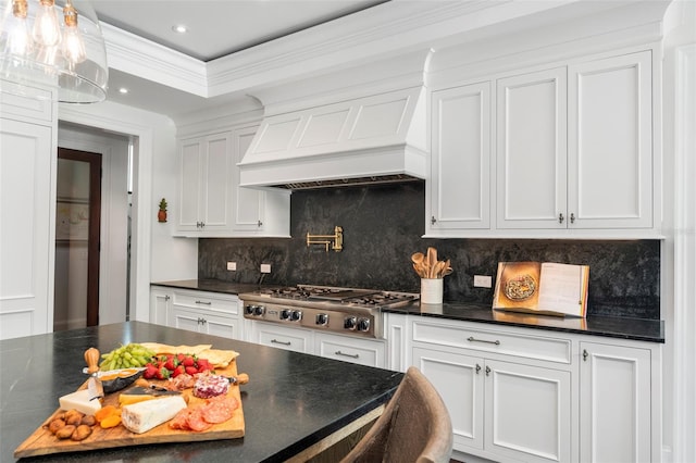 kitchen with tasteful backsplash, stainless steel gas stovetop, white cabinets, ornamental molding, and premium range hood