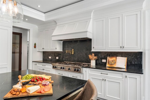 501 Harbor Point Rd, Longboat Key, FL 34228 - kitchen with stainless steel gas stovetop, custom range hood, backsplash, white cabinets, and recessed lighting