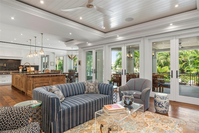 living room featuring french doors, ceiling fan with notable chandelier, dark hardwood / wood-style floors, and crown molding