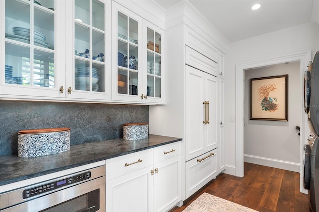 bar featuring oven, white cabinetry, dark hardwood / wood-style flooring, and tasteful backsplash